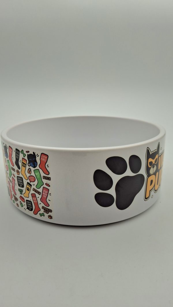 Gamelle blanche encéramique avec ,à gauche , des motifs puppy play colorés(chaussettes, slogans, têtes de chiot)et, à droite, une grande empreinte de patte noire en visuel central.