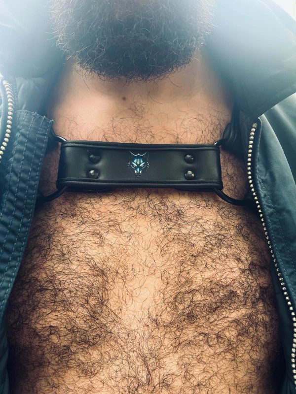 Harnais noir G.W.F en cuir porté torse nu avec une veste ouverte, logo tête de loup centré visible.