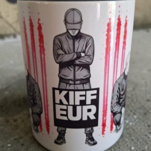 Mug Kiffeur 450 ml avec illustration streetwear fetish représentant un homme en survêtement et casquette, bras croisés, sur fond graphique noir, blanc et rose.