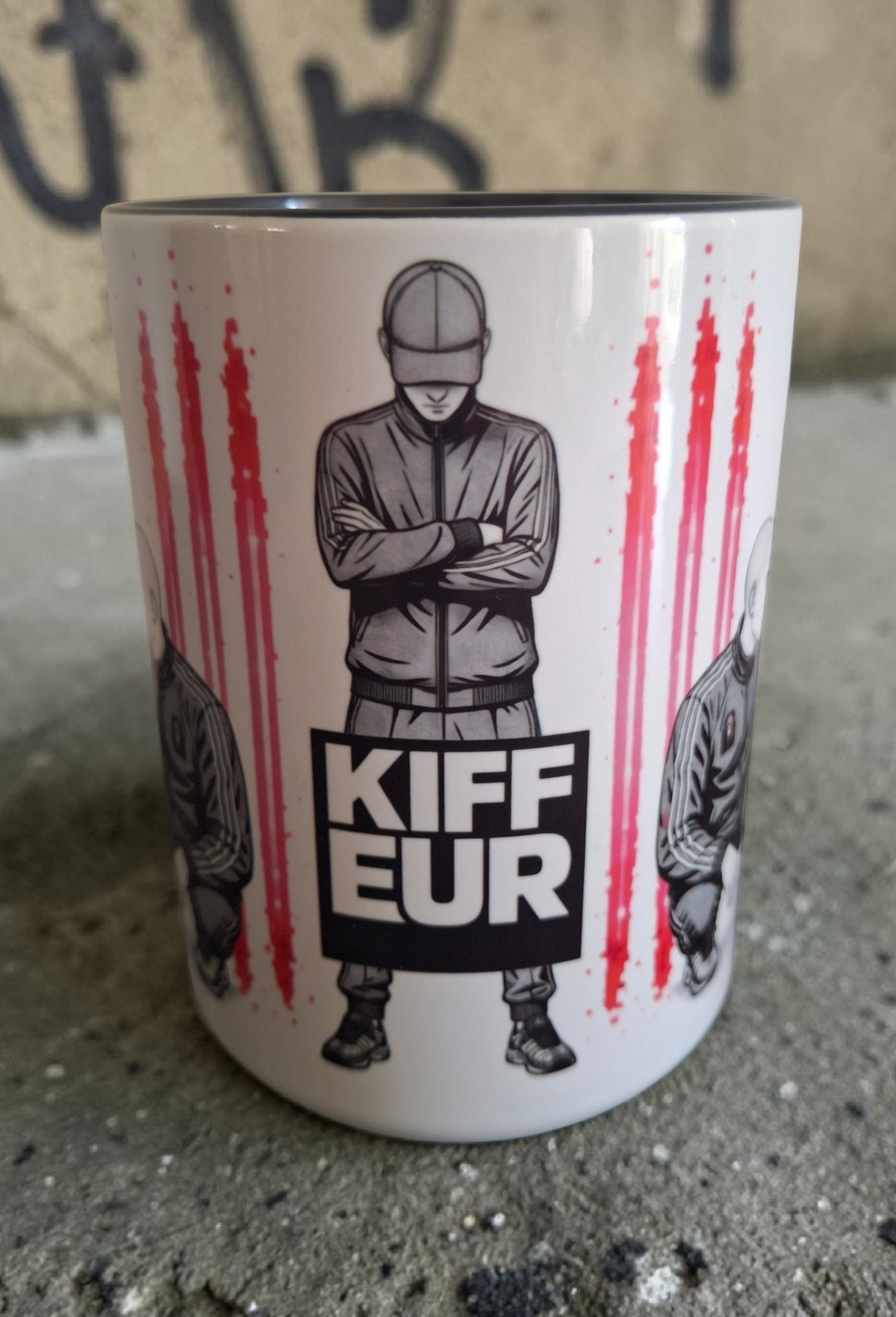 Mug Kiffeur 450 ml avec illustration streetwear fetish représentant un homme en survêtement et casquette, bras croisés, sur fond graphique noir, blanc et rose.